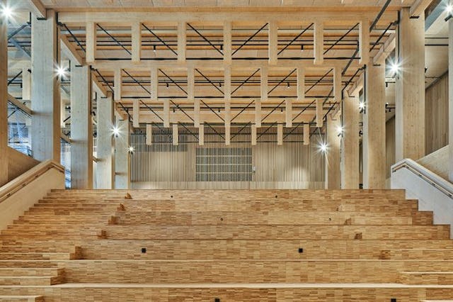 Modern auditorium med trätrappor och synliga takbjälkar.