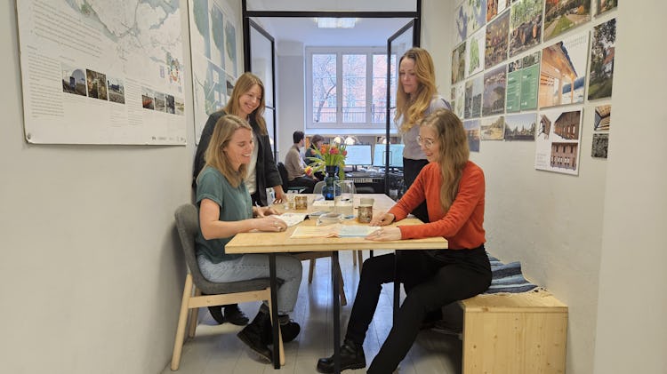 Fyra individer samarbetar runt ett bord i en ljus kontorsmiljö.