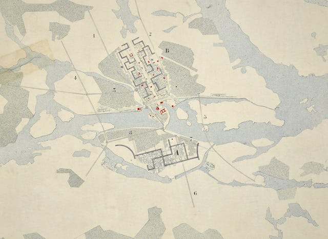 En äldre karta som visar en stadsplan med numrerade områden, vägar, vattendrag samt markerade byggnader eller platser.