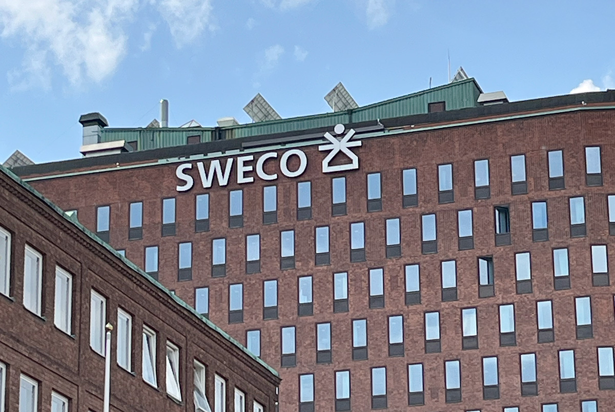 En tegelbyggnad med ordet "SWECO" och en geometrisk logotyp ovanpå.