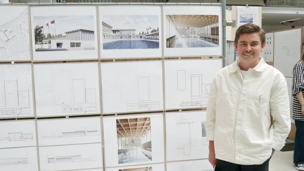 En man står framför en display med arkitektritningar och visualiseringar av ett byggnadsprojekt.