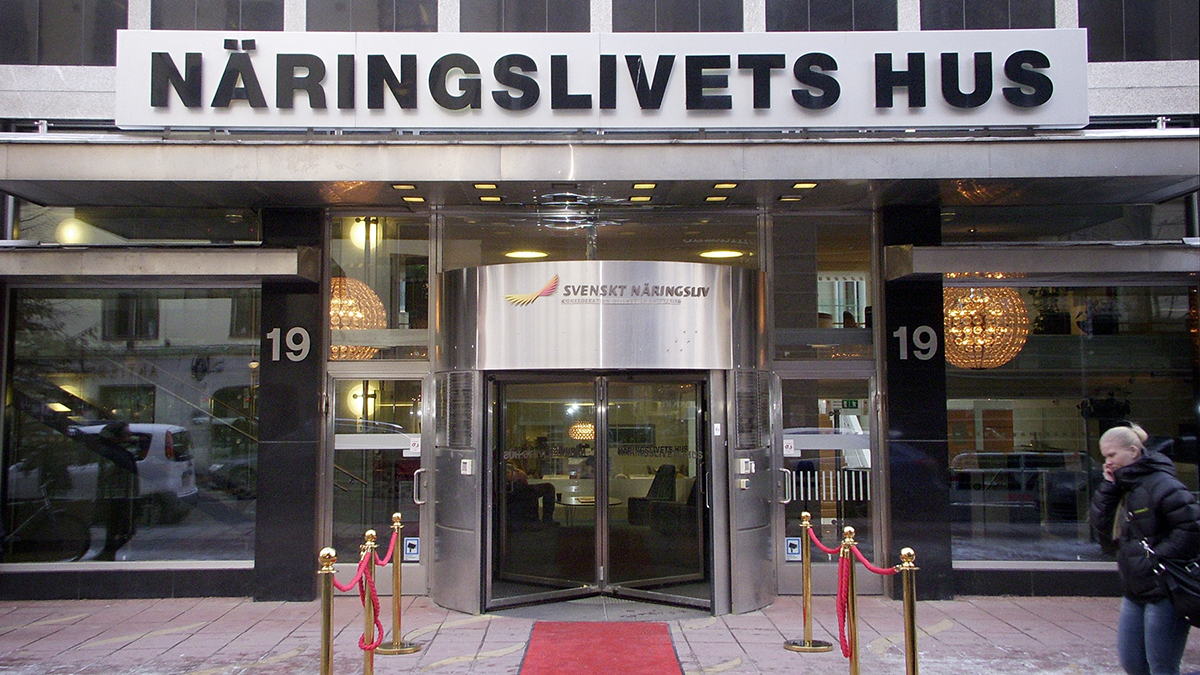 Ingången till Näringslivets Hus på Storgatan 19 med glasdörrar, röd matta, guldfärgade avspärrningar och en person som går förbi.