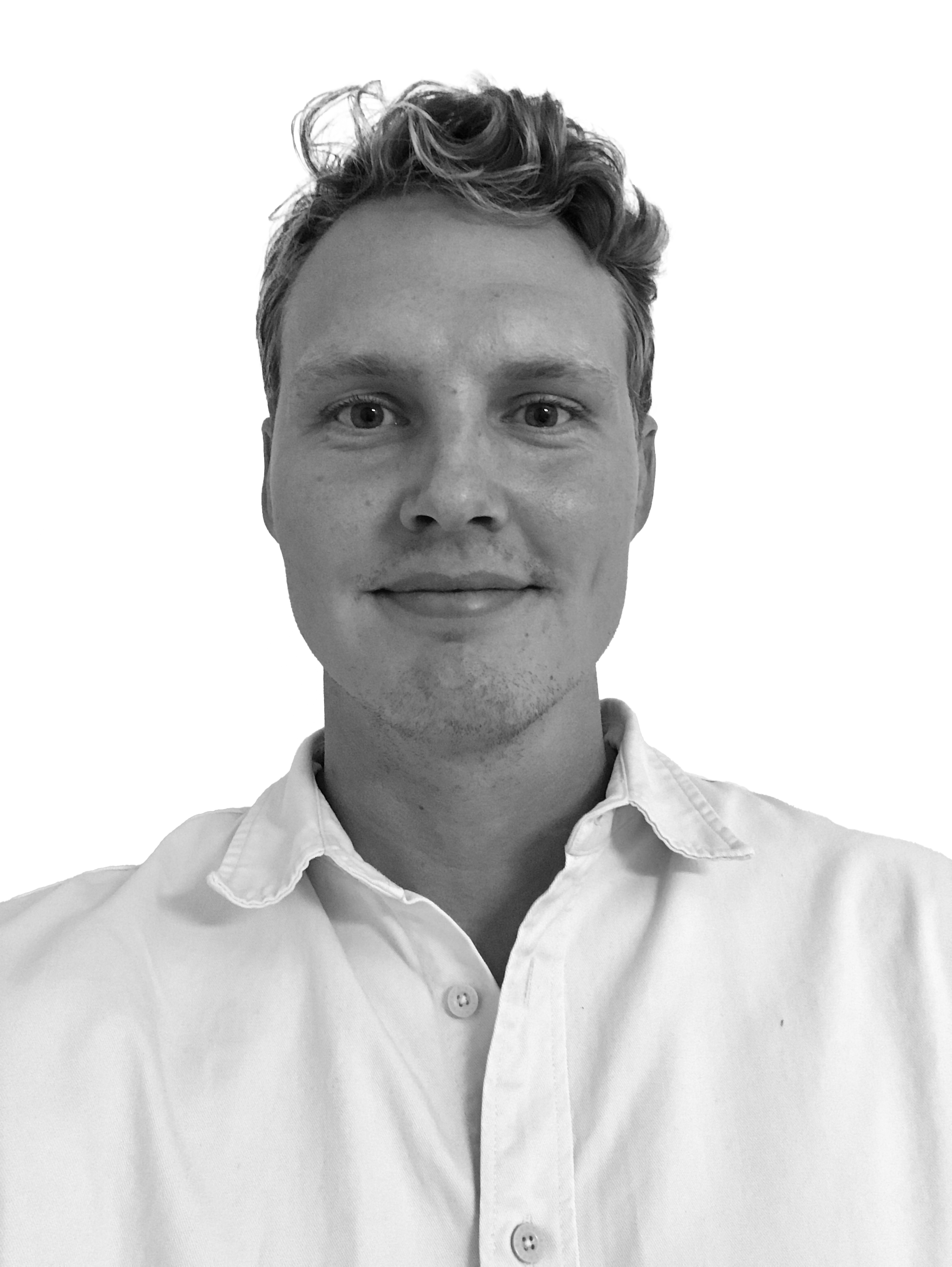 En person med kort, vågigt hår har på sig en ljus skjorta med knappar, står vänd framåt och ler svagt mot en vit bakgrund.