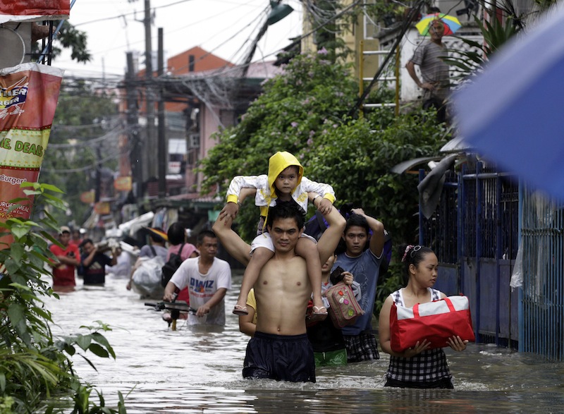 Familjer lämnar sina hem för att söka skydd på högre höjd undan översvämningarna i Pasig City, en förort till Filippinska huvudstaden Manilla. Foto: Pat Roque / AP