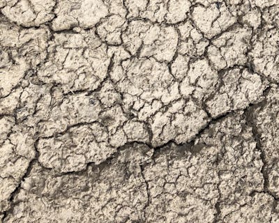 Närbild av torr, sprucken jord med en strukturerad yta.