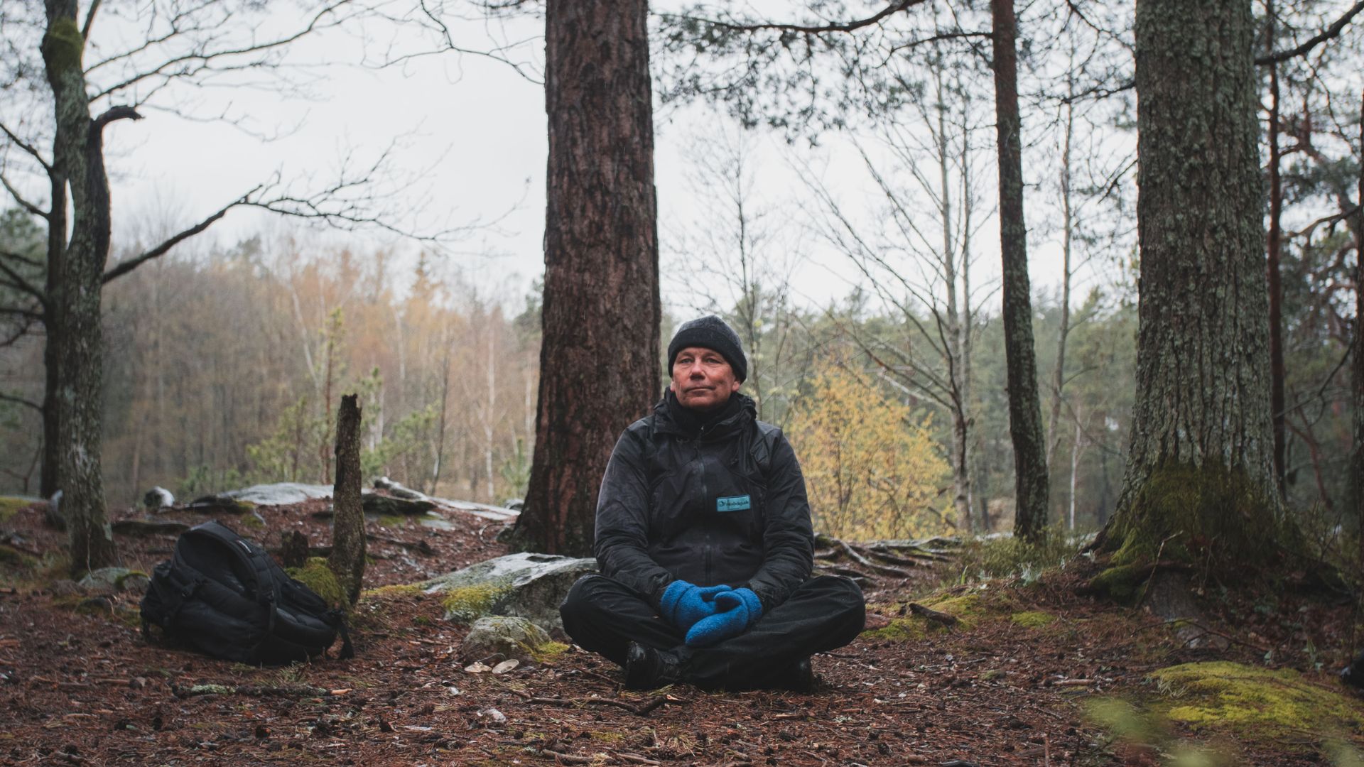 Bosse Rosén sitter på marken i en skog.
