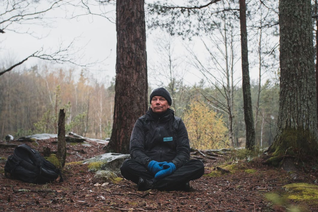 Bosse Rosén sitter på marken i en skog.