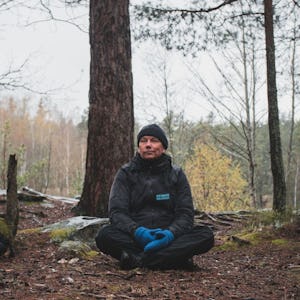Bosse Rosén sitter på marken i en skog.