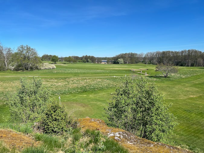 Utsikt över Sigtuna golfklubb med både ängar och hårdklippta banor.